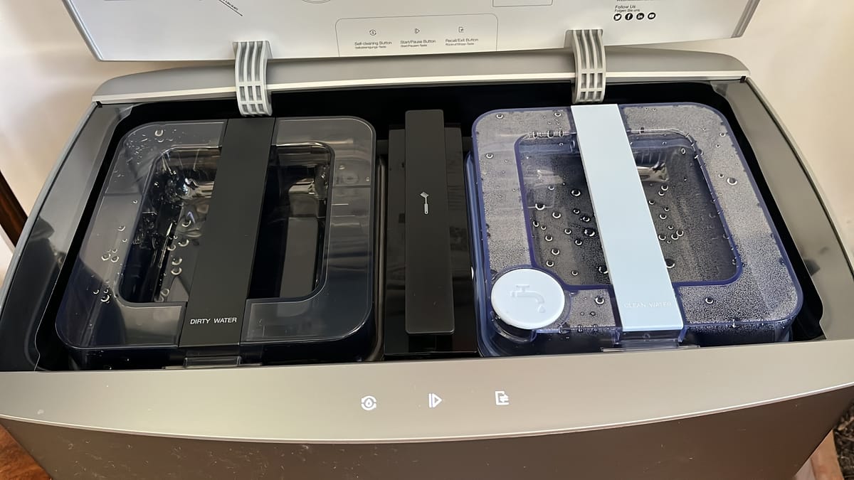 Eine Station eines Saugroboters mit aufgeklapptem Deckel. Frischwasser und Schmutzwasserbehälter sind sichtbar.
